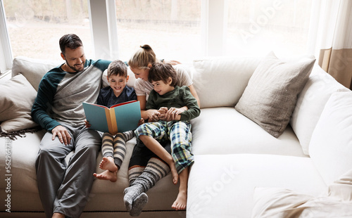 Happy, learning and parents reading a book with children for bonding, fun and quality time. Knowledge, information and boys excited about a story on the lounge sofa with their mother and father