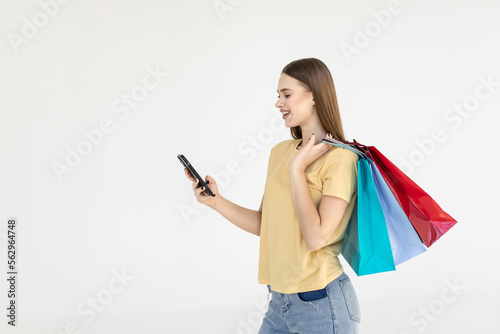 Portrait of a pretty woman holding shopping bags while using mobile phone isolated over white background