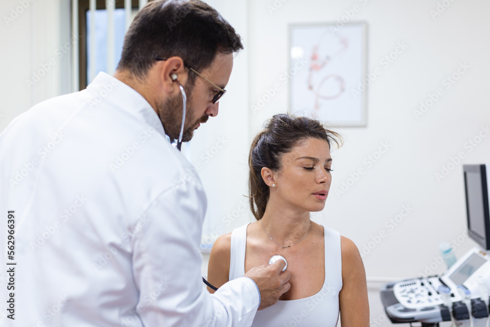 Fototapeta premium Caring doctor hold stethoscope listen to patient heart chest in hospital. Young woman do checkup examination in clinic. Healthcare concept.