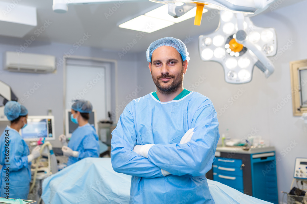 Portrait of male surgeon standing with arms crossed in operation theater at hospital. Team surgeons are performing an operation, middle aged doctor is looking at camera, in a modern operating room Portrait of male surgeon standing with arms crossed in operation theater at hospital. Team surgeons are performing an operation, middle aged doctor is looking at camera, in a modern operating room