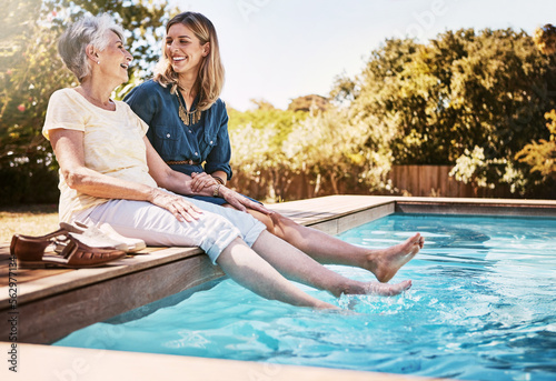 Women relax together by swimming pool, love and care, quality time during summer vacation. Elderly mother, daughter and vacation, content outdoor with pool and wellness lifestyle with happy family