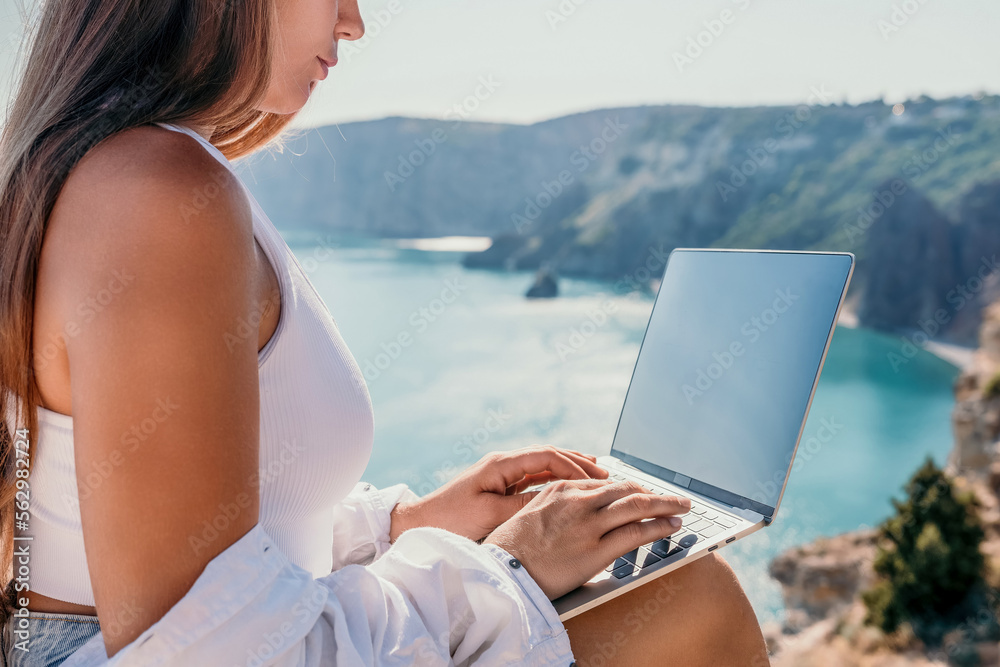 Woman sea laptop. Business woman in yellow hat freelancer with laptop working over blue sea beach. Girl relieves stress from work. Freelance, digital nomad, travel and holidays concept