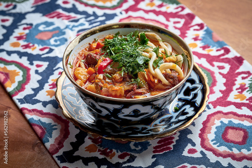 Laghman soup with meat, vegetables and pulled noodles served in plate.  photo