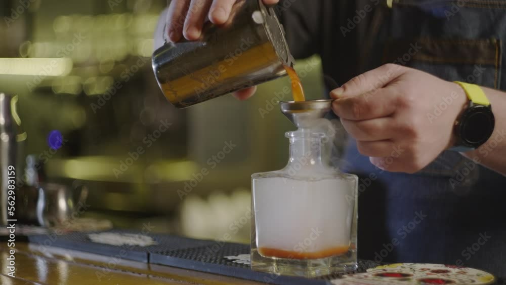 Slow motion video of a bartender pouring cocktail into a bottle. The process of making cocktails with tomato juice and vodka. A professional bartender is preparing a party at the bar. Slow motion video of a bartender pouring cocktail into a bottle. The process of making cocktails with tomato juice and vodka. A professional bartender is preparing a party at the bar.
