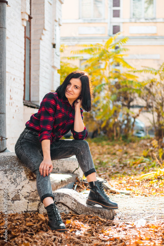 Autumn portrait of an attractive young woman sitting on old damaged stairs, outdoors