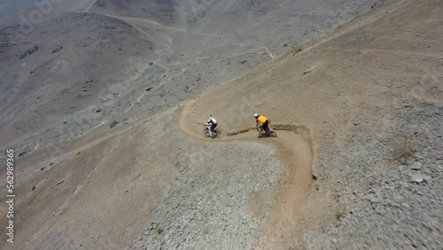 Dynamic drone shot following two mountain bikers down a rocky hill side. Drone swoops down then flies back high up keeping the bikers in focus. Recorded in 4k quality. Located in Lima, Peru. photo