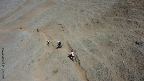 A group of mountain bikers starting the downhill route. They quickly pick up speed going down the dirt trail in the hillside. Drone follows behind. Recorded in 4k quality. Located in Lima, Peru. photo