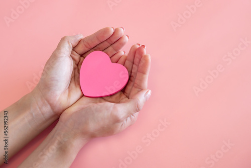 Valokuva Woman hands holding a pink heart symbol