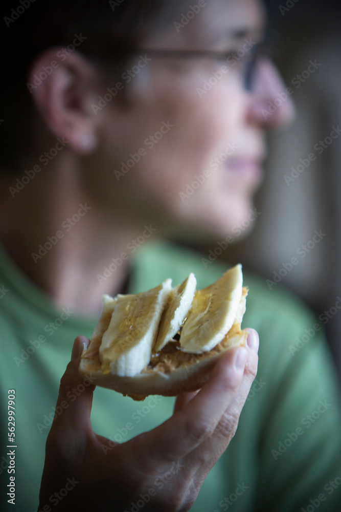 A woman holding a open face peanut butter and banana sandwich. A woman holding a open face peanut butter and banana sandwich.