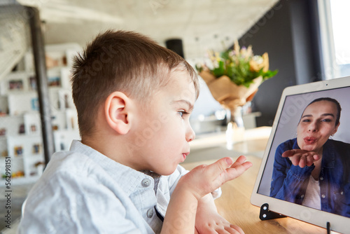 Kind macht Videoschat mit seiner Mutter über Tablet Computer photo