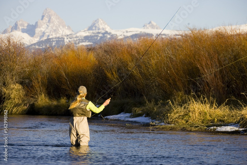 Woman fishing at sunset with mountains in background, Idaho photo