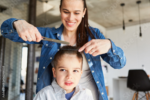 Mutter beim Haare schneiden von Kind zu Hause photo