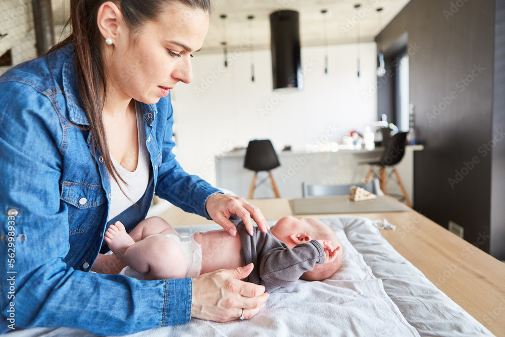 Fürsorgliche Mutter zieht Baby einen Pullover an Fürsorgliche Mutter zieht Baby einen Pullover an