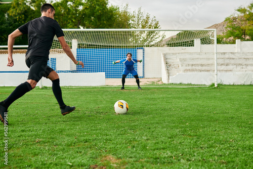 A soccer player takes a penalty kick against a goalkeeper