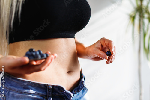 First month of pregnancy. Giovane ragazza con fisico sportivo tiene in mano mirtilli. Motherhood and healthy concept.