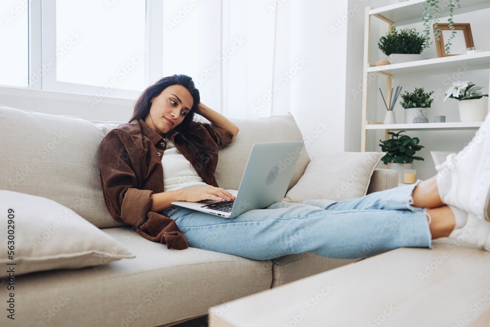 Woman freelancer on day off sitting on sofa with laptop at home online shopping on internet, smile Woman freelancer on day off sitting on sofa with laptop at home online shopping on internet, smile