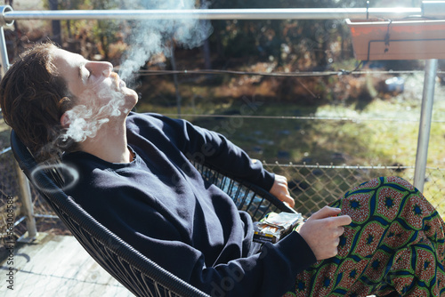 young male person on the balcony smoking a cigarette 