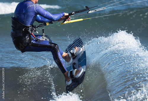 Athletic man jumping on kite surf board on a sea waves. Kiteboarding man among waves quickly goes. Watersport adrenaline fun adventure acitivity photo