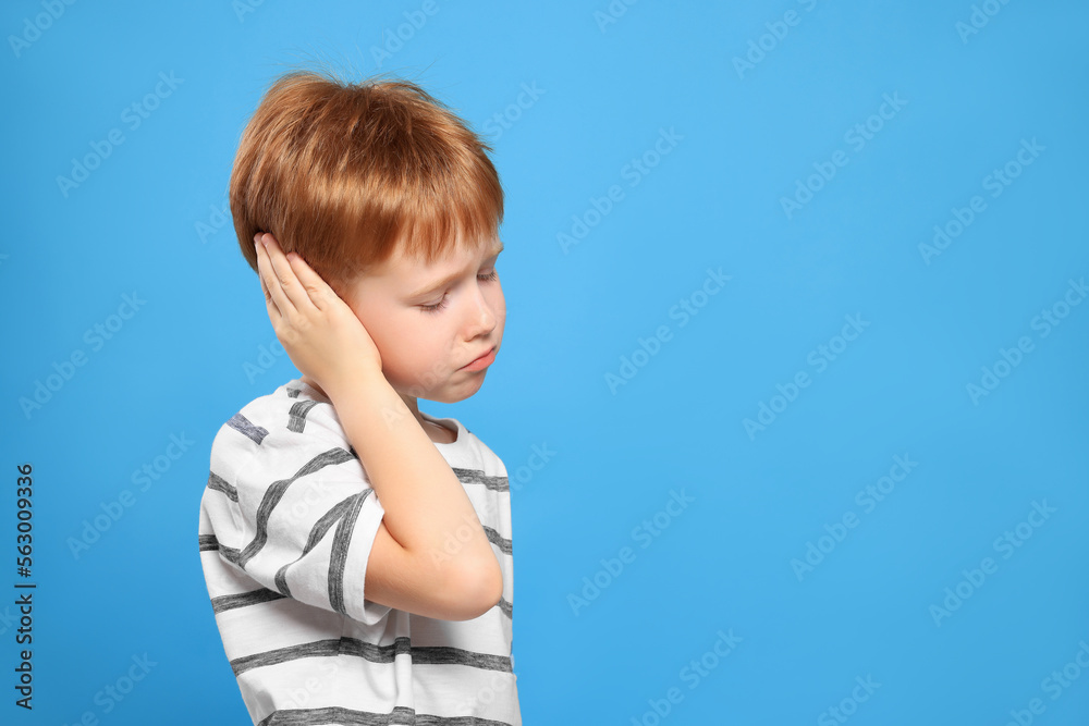 Little boy suffering from ear pain on light blue background. Space for text Little boy suffering from ear pain on light blue background. Space for text