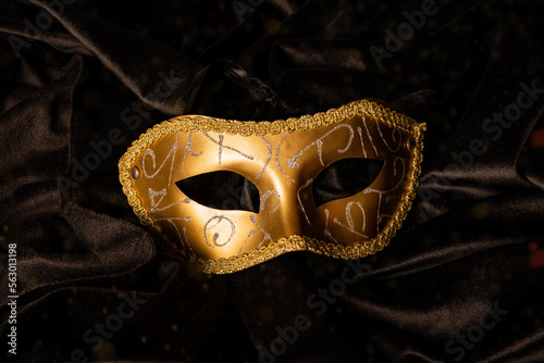Closeup of golden carnival mask on black curtain table
