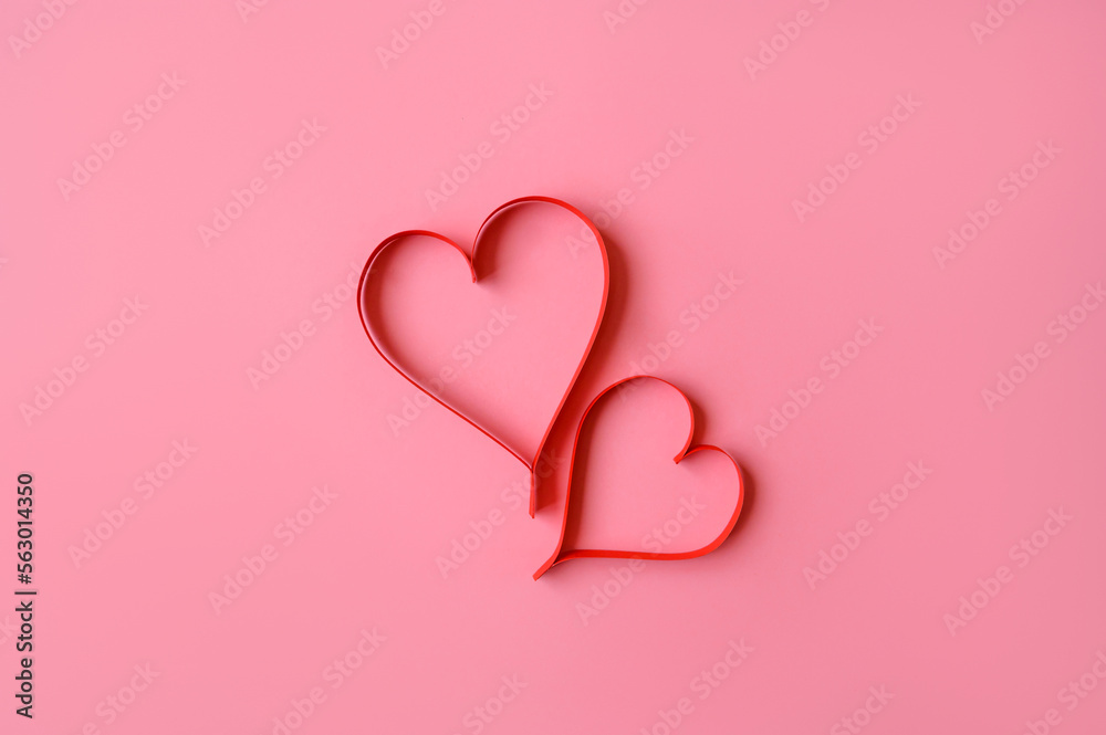 Two red hearts made of paper on a pink background. Background for a valentine's postcard. valentine day. Love concept.