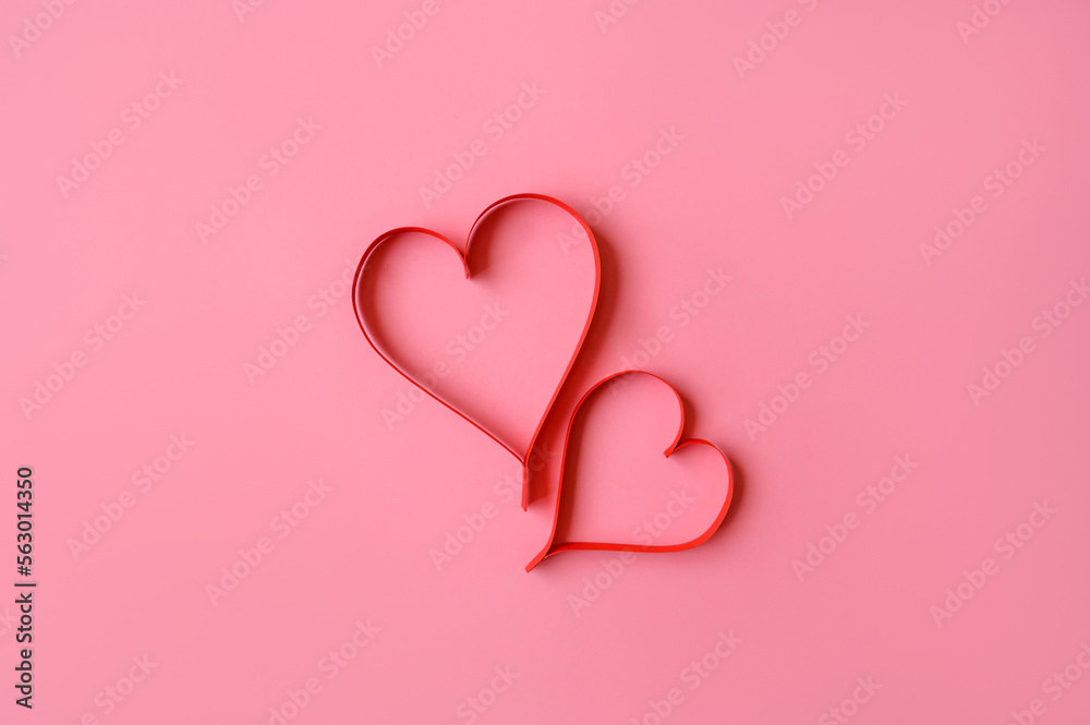 Two red hearts made of paper on a pink background. Background for a valentine's postcard. valentine day. Love concept. Two red hearts made of paper on a pink background. Background for a valentine's postcard. valentine day. Love concept.