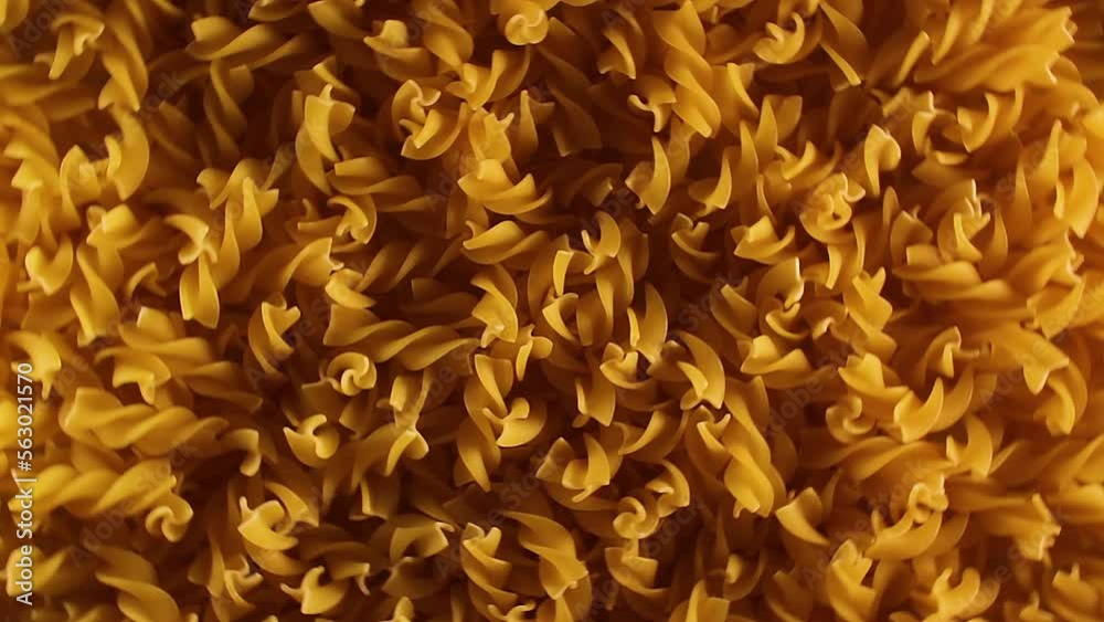 Uncooked Fusilli Pasta - Top View, Low Key Light. Fat and Unhealthy Food. Dry Spiral Macaroni, Rotating Background. Italian Culture and Cuisine. Raw Golden Pasta Pattern. Left Rotation Uncooked Fusilli Pasta - Top View, Low Key Light. Fat and Unhealthy Food. Dry Spiral Macaroni, Rotating Background. Italian Culture and Cuisine. Raw Golden Pasta Pattern. Left Rotation