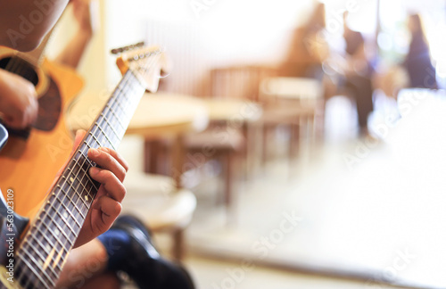 Selective focus of finger style playing electric guitar with blurred vie wof people talking in cafe photo