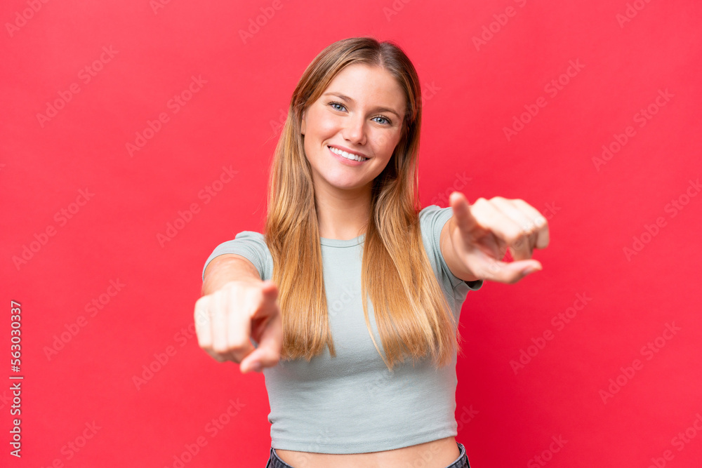 Young beautiful woman isolated on red background pointing front with happy expression Young beautiful woman isolated on red background pointing front with happy expression