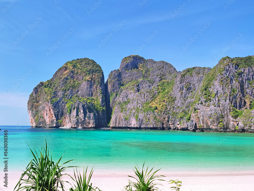 Rocks with green plants in the turquoise ocean against the blue sky in Asia
