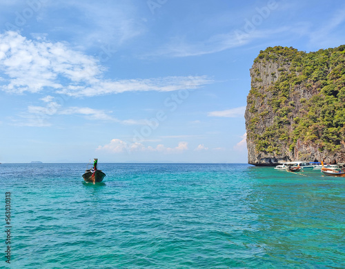  The sea in the tropics with a boat for tourists and a rock in the background