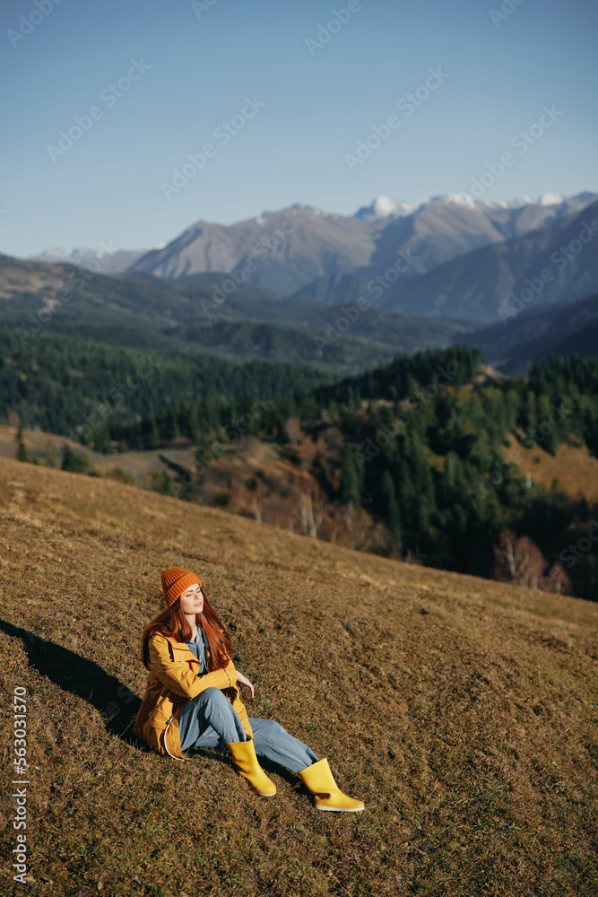 Woman full-length sitting resting on a hill and looking at the mountains happy nature trip on a hike in the fall, freedom lifestyle in motion