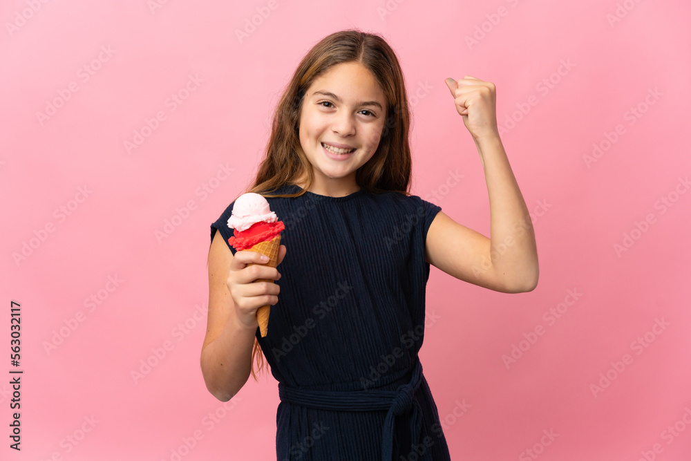 Child with a cornet ice cream over isolated pink background celebrating a victory Child with a cornet ice cream over isolated pink background celebrating a victory