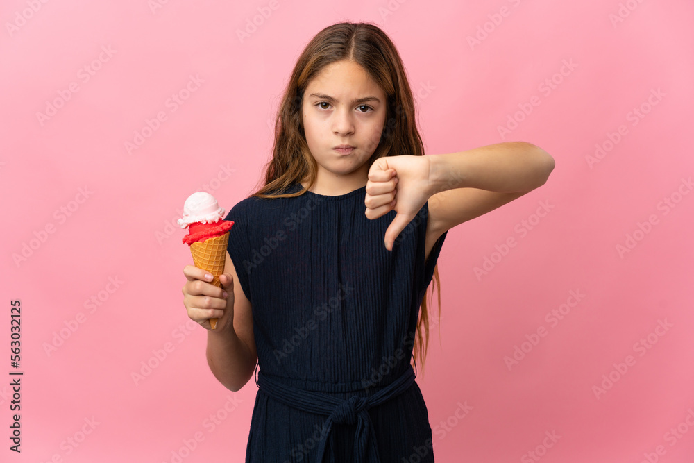 Child with a cornet ice cream over isolated pink background showing thumb down with negative expression Child with a cornet ice cream over isolated pink background showing thumb down with negative expression