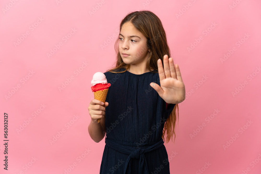 Child with a cornet ice cream over isolated pink background making stop gesture and disappointed Child with a cornet ice cream over isolated pink background making stop gesture and disappointed