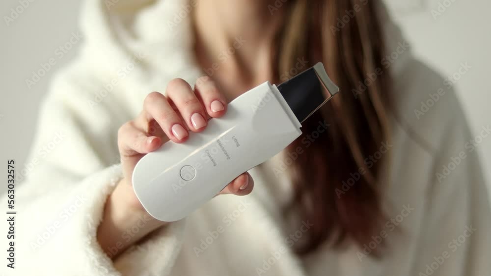 Ultrasonic facial scrubber for cleansing black dots and acne in a woman's hand close-up, selective focus. Ultrasonic facial scrubber for cleansing black dots and acne in a woman's hand close-up, selective focus.
