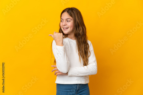 Child over isolated yellow background pointing to the side to present a product