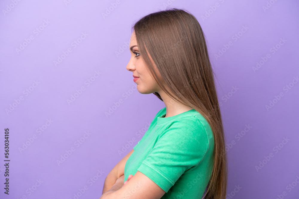 Young caucasian woman isolated on purple background in lateral position Young caucasian woman isolated on purple background in lateral position