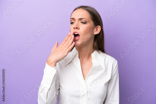Young caucasian woman isolated on purple background yawning and covering wide open mouth with hand