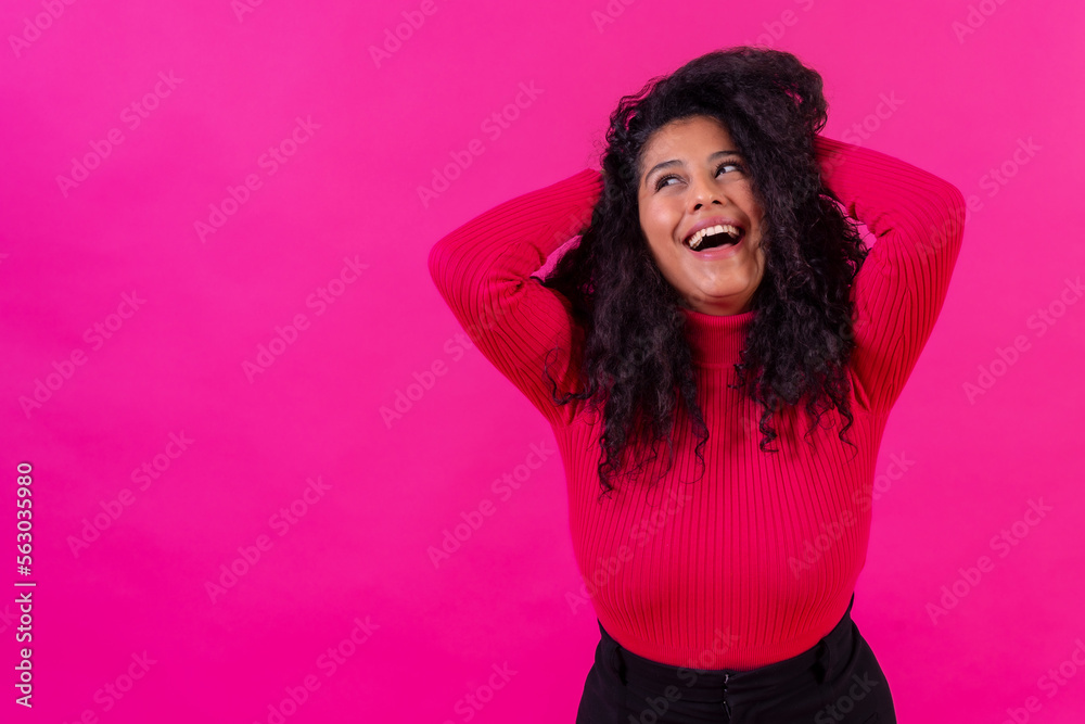 Curly-haired woman smiling on a pink background, studio shot, lifestyle
