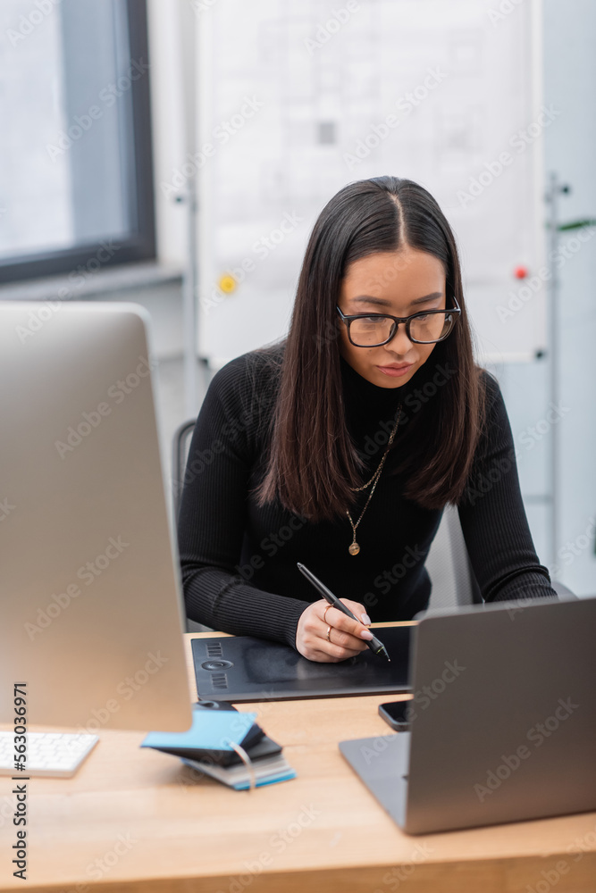 Asian interior designer using graphic tablet near laptop and computer in office. Asian interior designer using graphic tablet near laptop and computer in office.