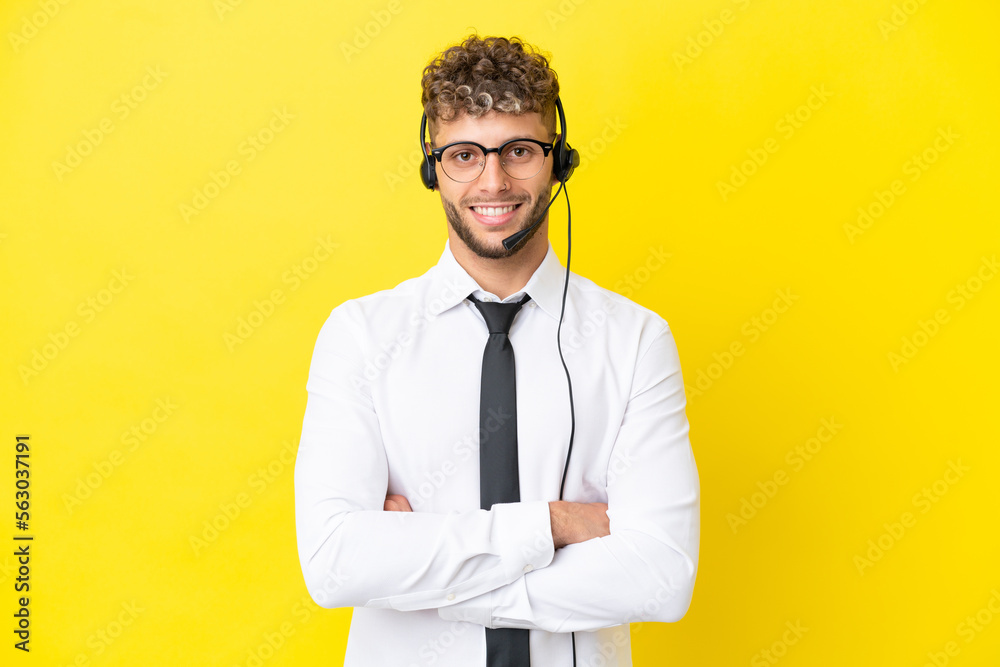 Telemarketer blonde man working with a headset isolated on yellow background keeping the arms crossed in frontal position Telemarketer blonde man working with a headset isolated on yellow background keeping the arms crossed in frontal position