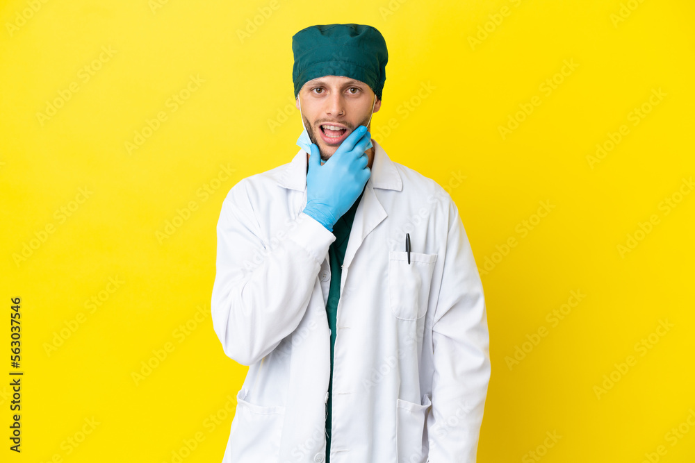 Surgeon blonde man in green uniform isolated on yellow background surprised and shocked while looking right Surgeon blonde man in green uniform isolated on yellow background surprised and shocked while looking right