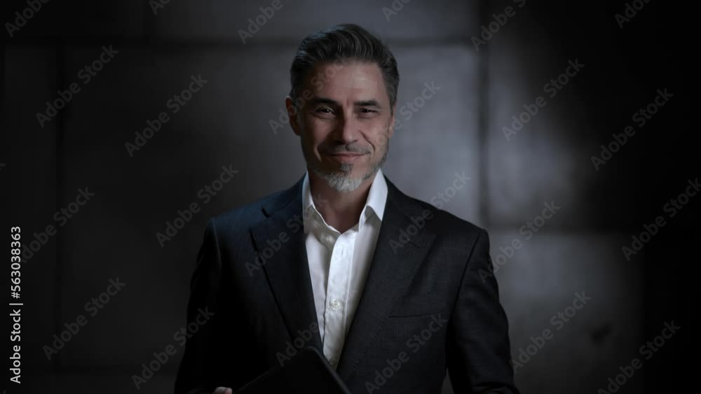 Portrait of happy mature businessman with tablet computer. Entrepreneur standing in front of dark loft wall. Older, middle aged, mid adult, man in his 40s or 50s in shirt and jacket, business casual. Portrait of happy mature businessman with tablet computer. Entrepreneur standing in front of dark loft wall. Older, middle aged, mid adult, man in his 40s or 50s in shirt and jacket, business casual.