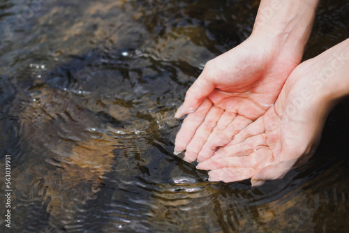 A woman's cupped hand is holding clean natural water in the river, copy space