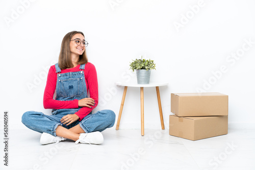 Young caucasian woman sitting on the floor among boxes happy and smiling