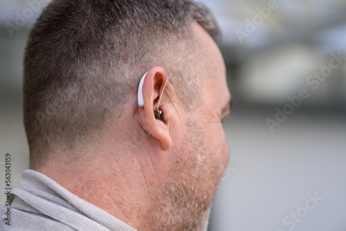 Rear view of a man with a hearing aid in his ear