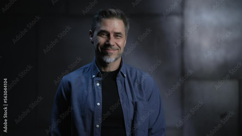 Portrait of happy mature casual man, smiling, standing in front of dark loft wall. Older, middle aged, mid adult, man in his 40s or 50s in shirt. Portrait of happy mature casual man, smiling, standing in front of dark loft wall. Older, middle aged, mid adult, man in his 40s or 50s in shirt.