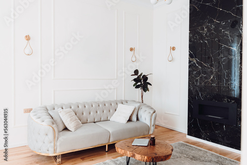 Stylish living room details and modern design with sofa, details of couch and pillows. Boho design, comfortable sofa with textures and modern furniture next to fireplace