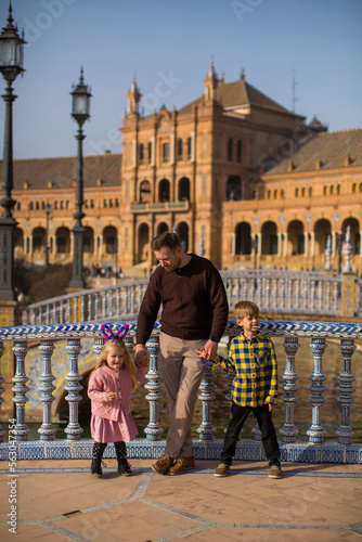 SEVILLE, SPAIN father and kids play outside Plaza Espana  in Seville, Spain. It is a landmark example of the Renaissance Revival style in Spanish architecture..Important information photo